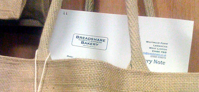 A breadbasket leaflet sticking out of the top of a Breadshare Bakery bread bag